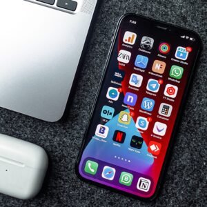 Flat lay of a smartphone, laptop, and earphones on a grey surface. Perfect for tech and gadget themes.